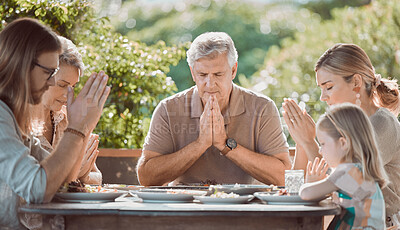 Buy stock photo Shot of a family sitting together and praying before lunch