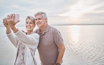 Buy stock photo Shot of a mature couple taking a selfie while at the beach