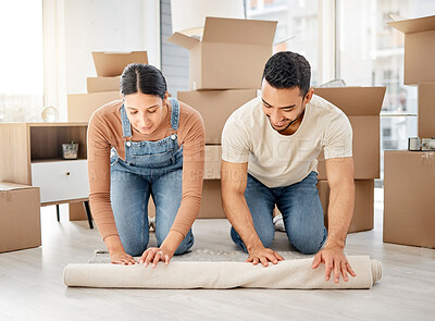 Buy stock photo Shot of a young couple rolling out a carpet together in their new home