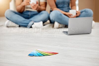 Buy stock photo Closeup shot of colour swatches on the floor with an unrecognisable couple using a laptop in the background while moving house