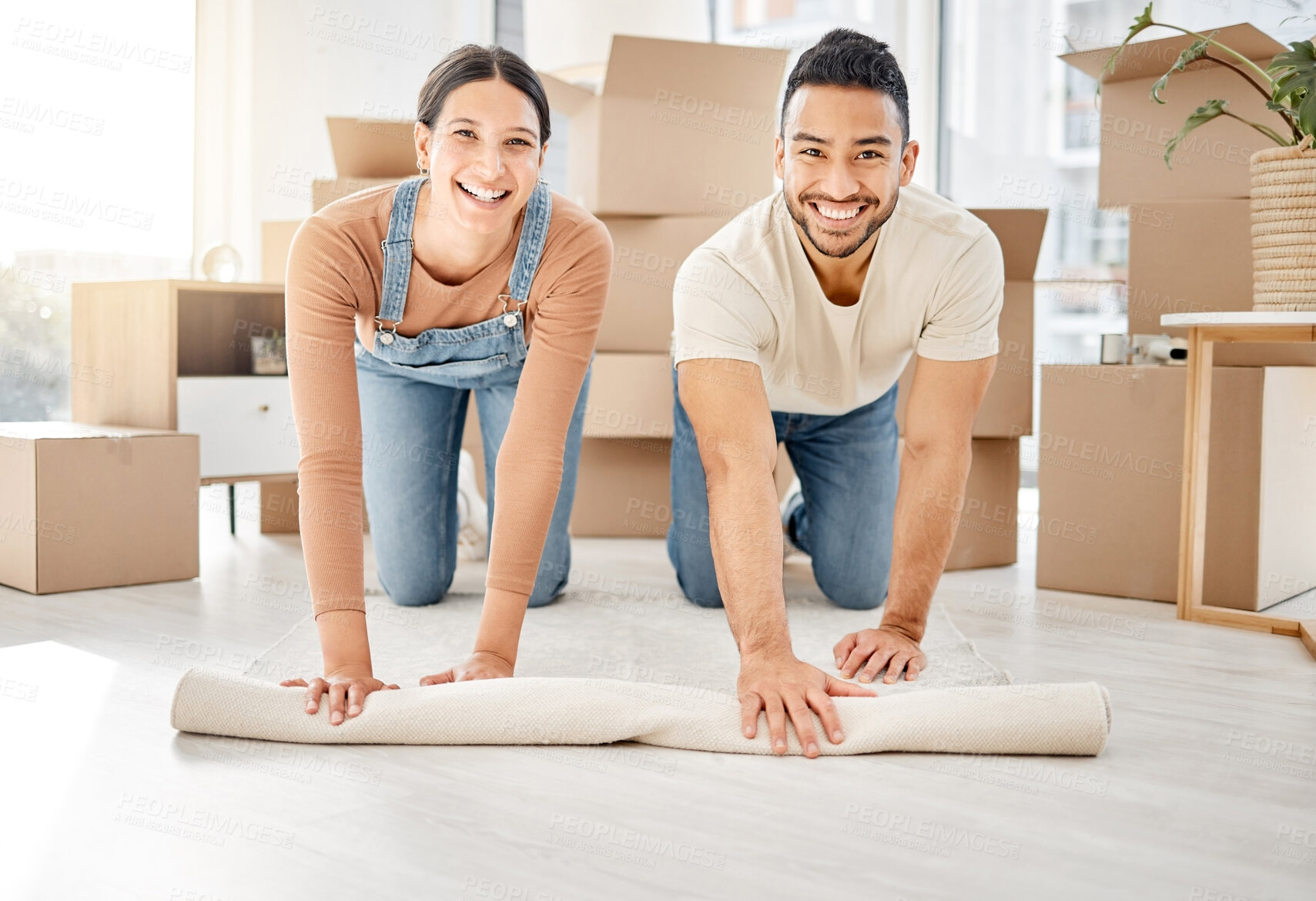 Buy stock photo Portrait of a young couple rolling out a carpet together in their new home
