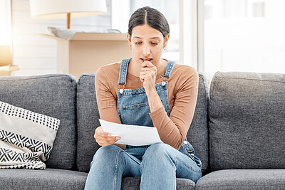 Buy stock photo Shot of a young woman anxiously biting her nails and reading a letter while moving house
