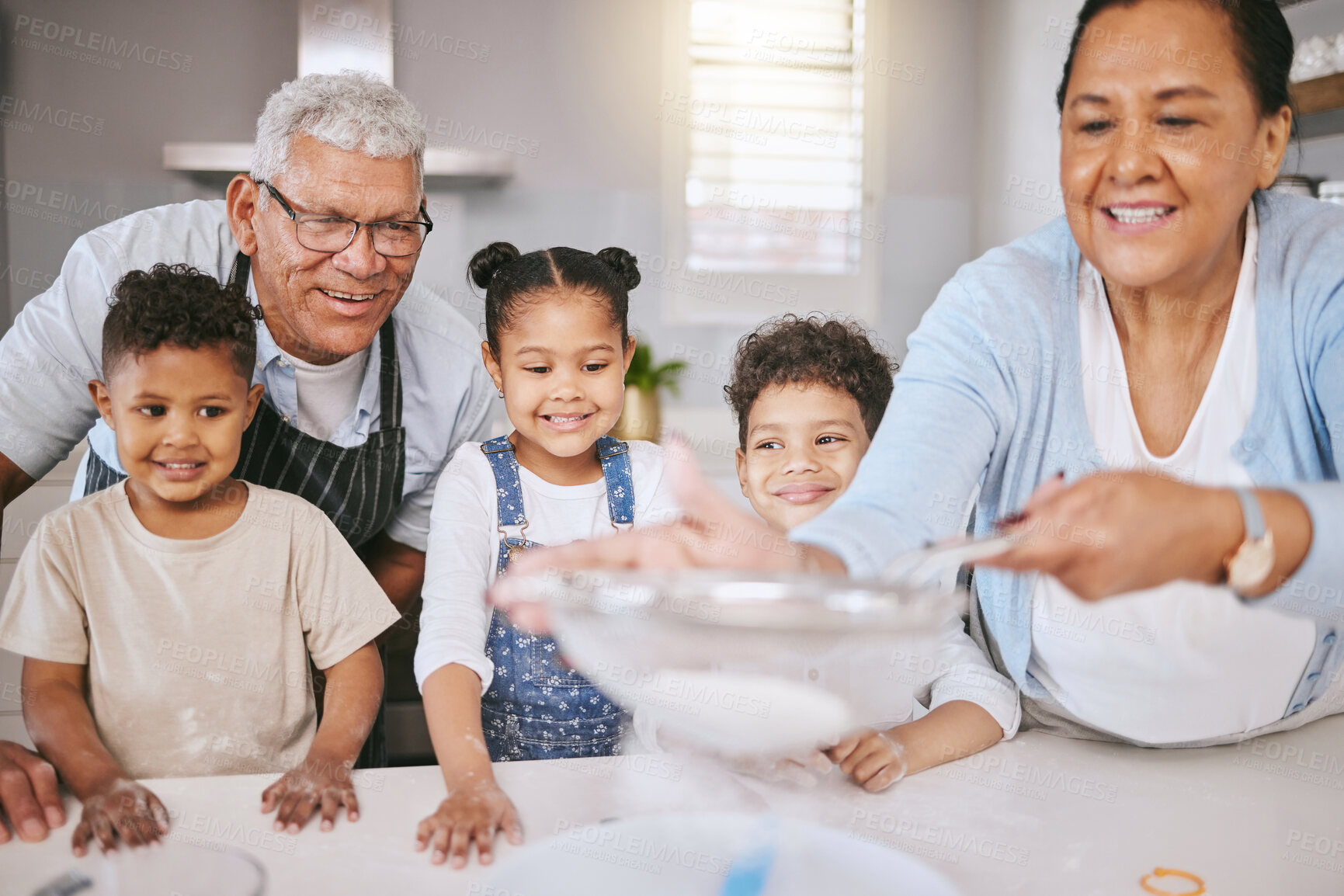 Buy stock photo Shot of a mature couple baking with their grandkids at home