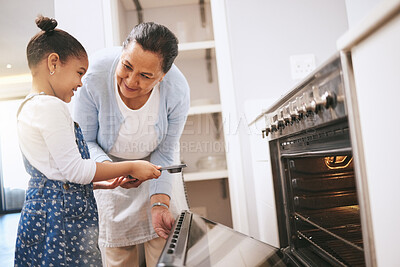 Buy stock photo Shot of a mature woman helping her grandchild safely open the oven at home