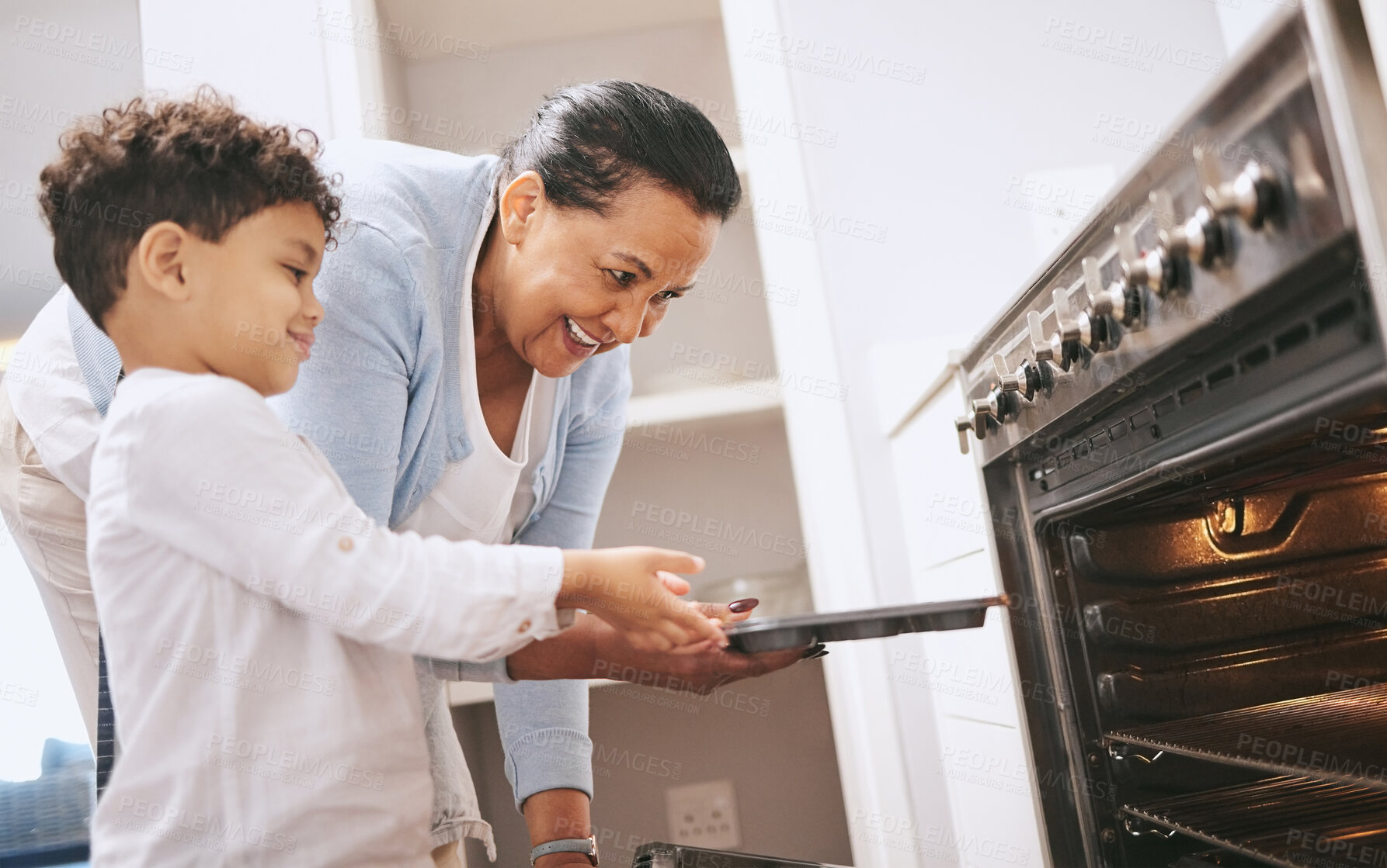 Buy stock photo Shot of a mature woman helping her grandchild safely open the oven at home