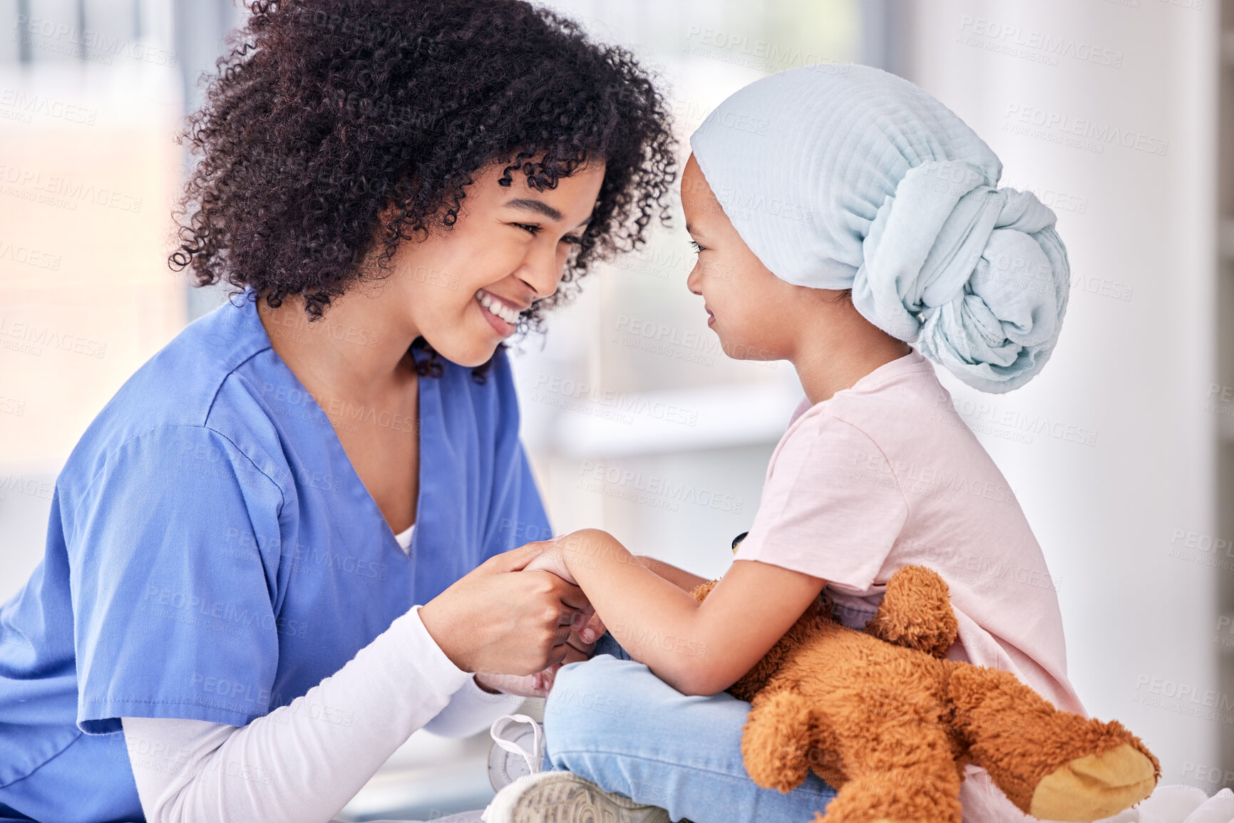 Buy stock photo Support, nurse and child holding hands on bed in hospital for children, health and smile at cancer treatment clinic. Pediatrics, healthcare and kids, nursing caregiver together with young patient.