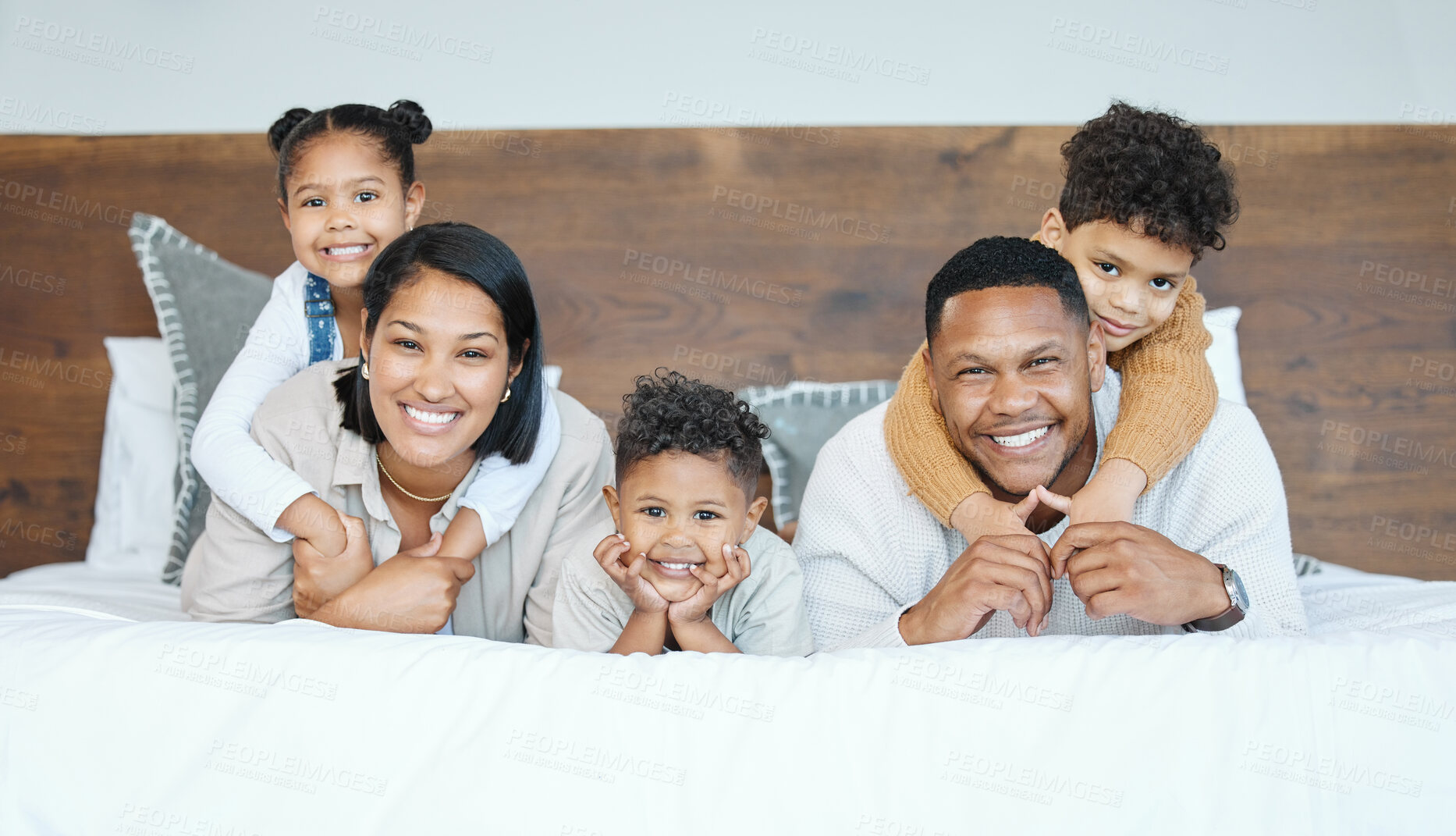 Buy stock photo Parents, children and lying on bed for portrait with piggy back, care and bonding with love in family home. Kids, father and mother with smile, connection and relax with pride at apartment in Mexico