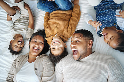 Buy stock photo Parents, children and above bed with laughing, love and funny memory for connection in morning at family house. Father, mother and kids with lying, excited and happy for comic joke at apartment