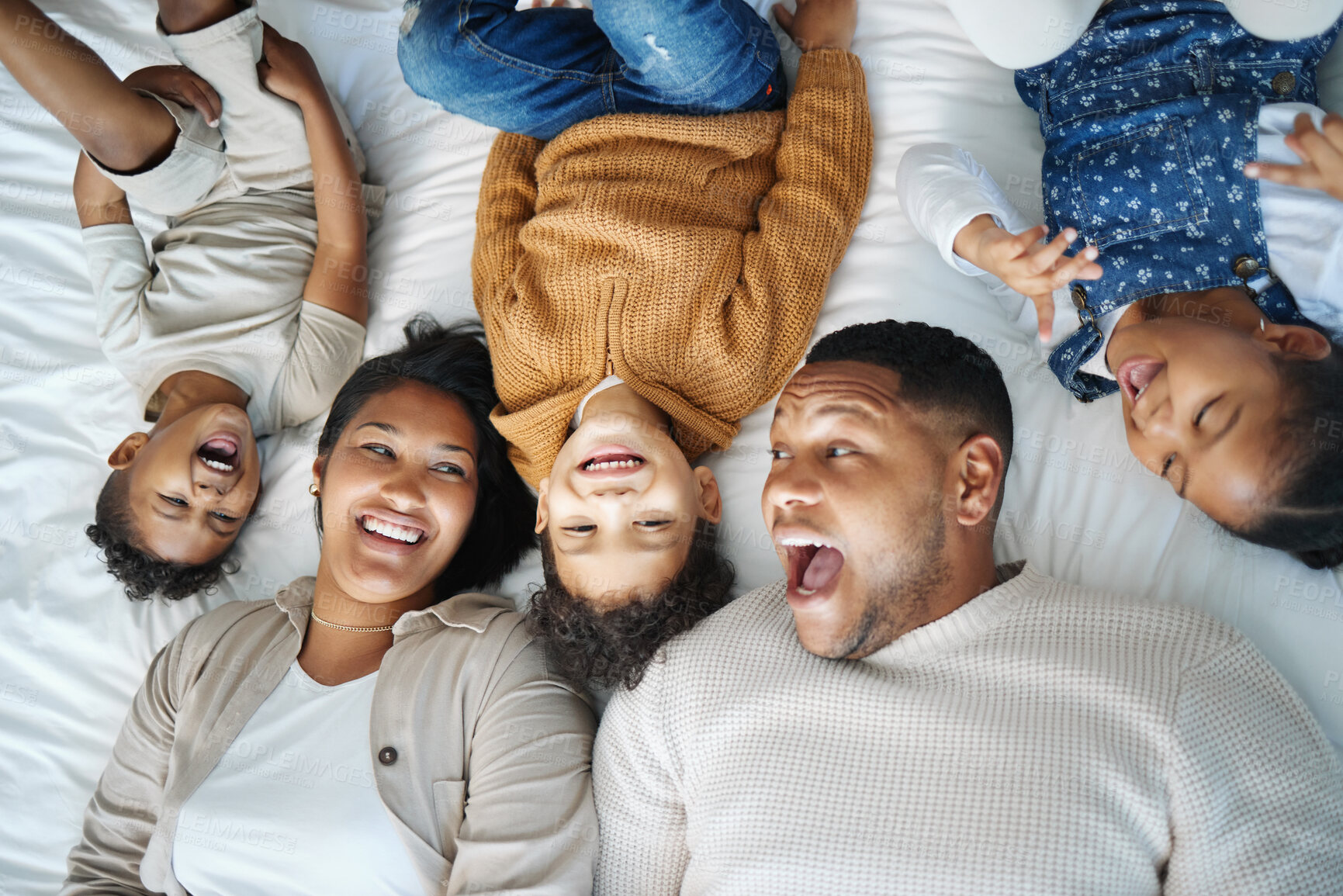 Buy stock photo Parents, children and above bed with laughing, love and funny memory for connection in morning at family house. Father, mother and kids with lying, excited and happy for comic joke at apartment