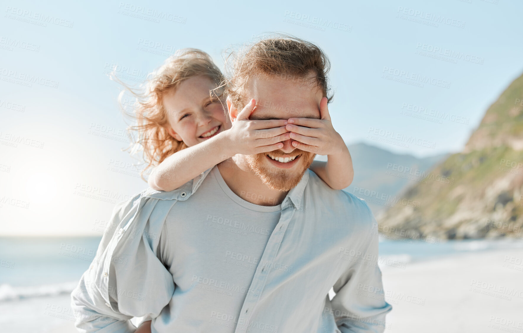 Buy stock photo Shot of a little girl covering her father's eyes while playing on the beach