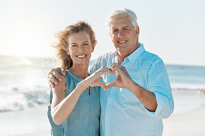 Buy stock photo Shot of a mature couple forming a heart with their hands while at the beach