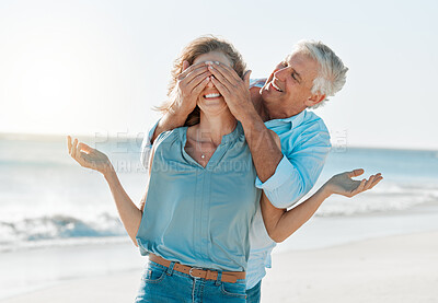 Buy stock photo Shot of a man covering his wife's eyes while on the beach