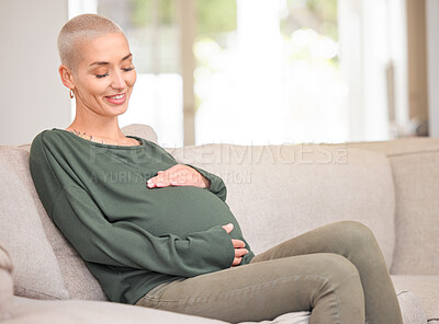 Buy stock photo Cropped shot of an attractive young pregnant woman rubbing her belly while sitting on the sofa at home