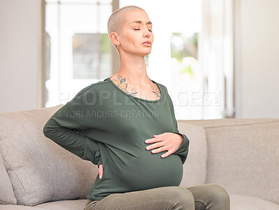 Buy stock photo Cropped shot of an attractive young pregnant woman looking uncomfortable while sitting on the sofa at home