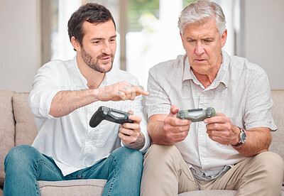 Buy stock photo Cropped shot of a handsome young man showing his senior father how to play video games at home