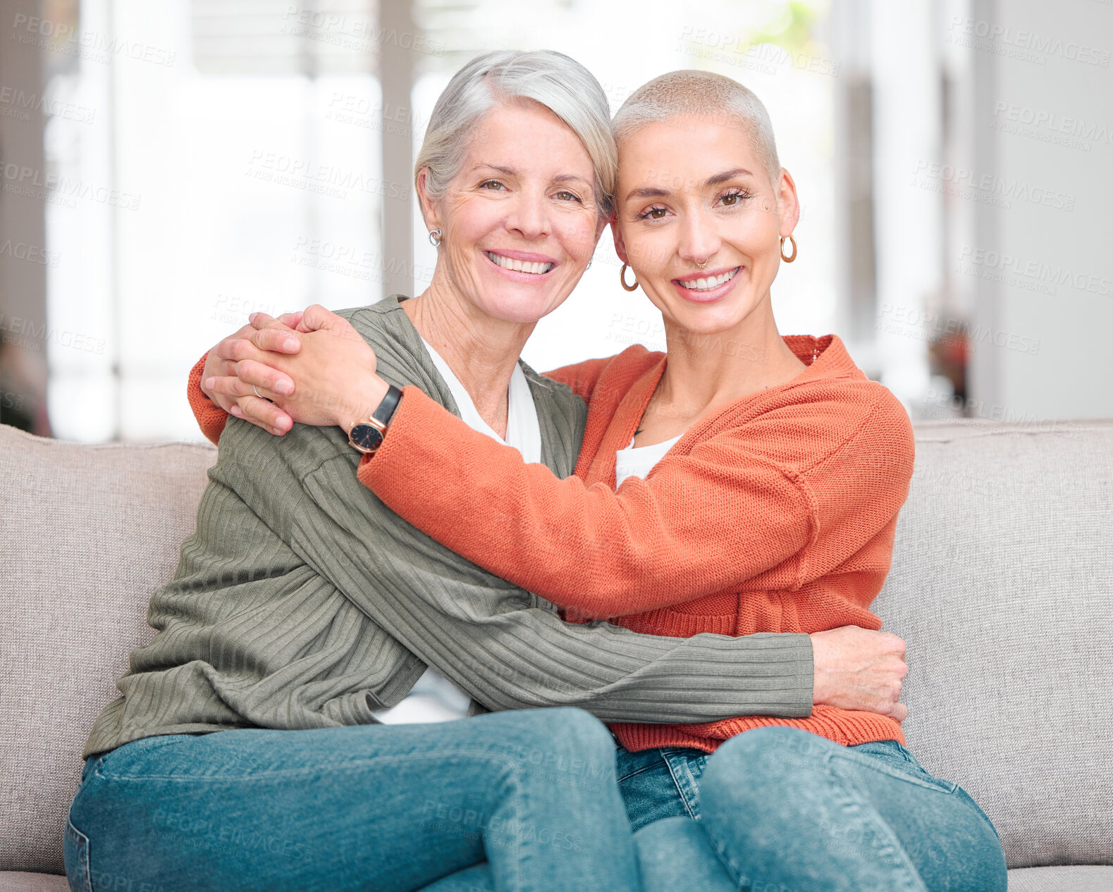 Buy stock photo Cropped portrait of an attractive young woman and her senior mother sitting on the sofa at home