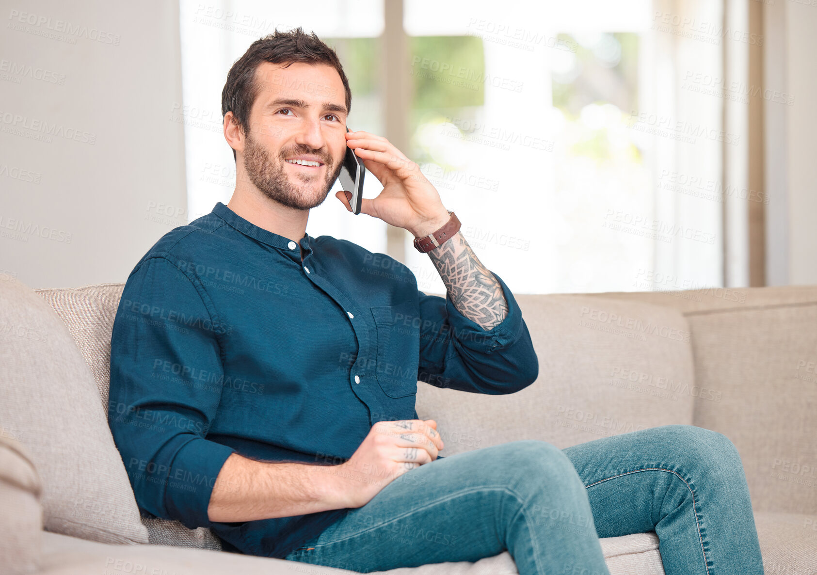 Buy stock photo Cropped portrait of a handsome young man making a phonecall while sitting on the sofa at home