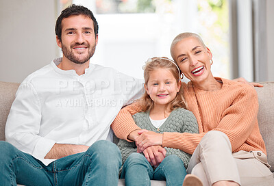 Buy stock photo Portrait of a young family bonding while sitting on the sofa at home