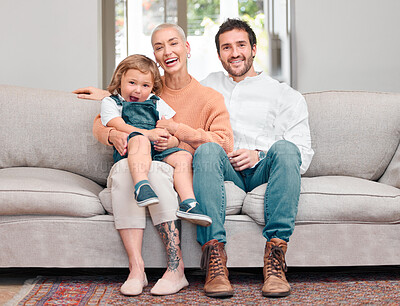 Buy stock photo Portrait of a young family bonding while sitting on the sofa at home