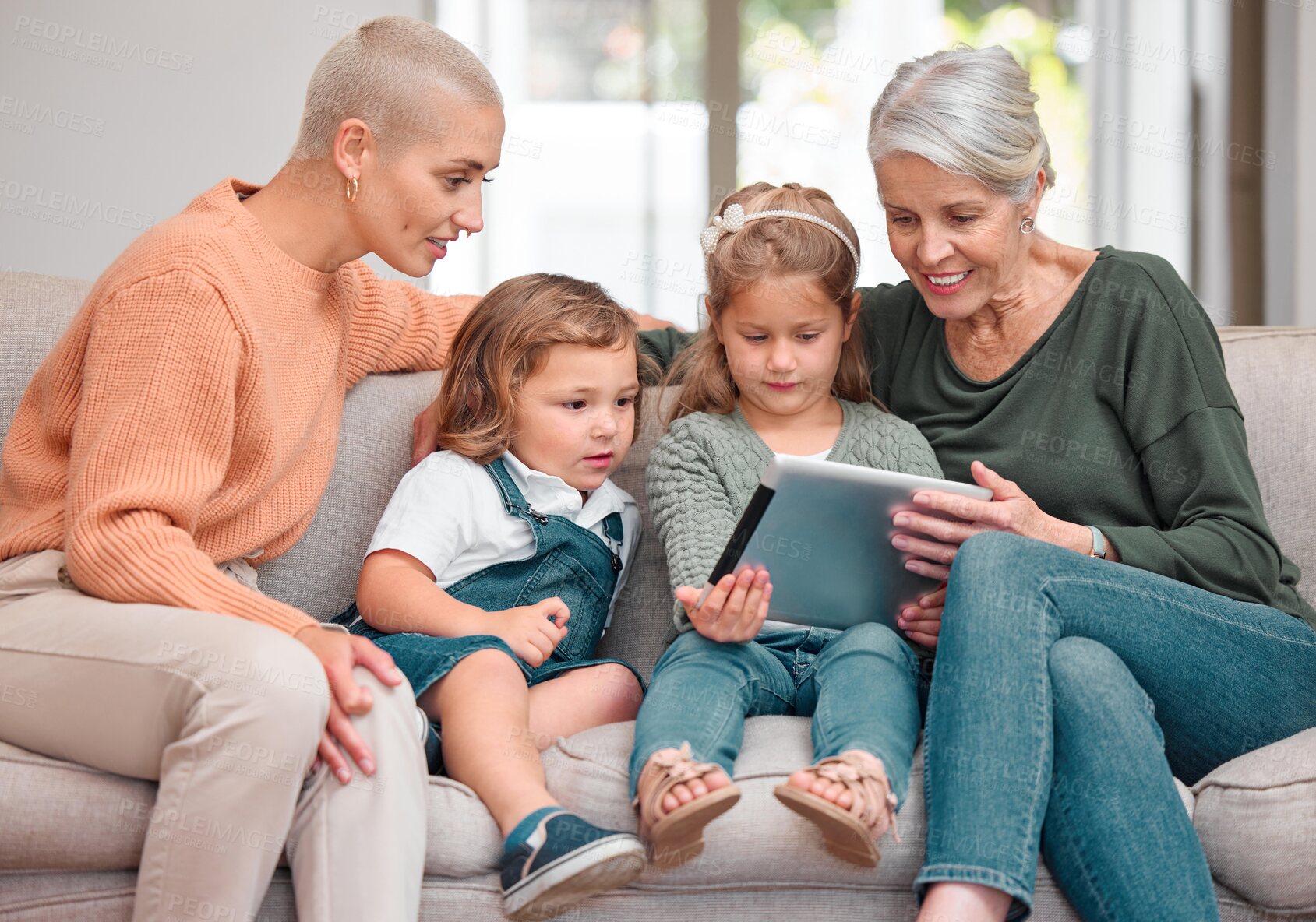 Buy stock photo Shot of a mature woman bonding with her daughter and grandkids while using a digital tablet
