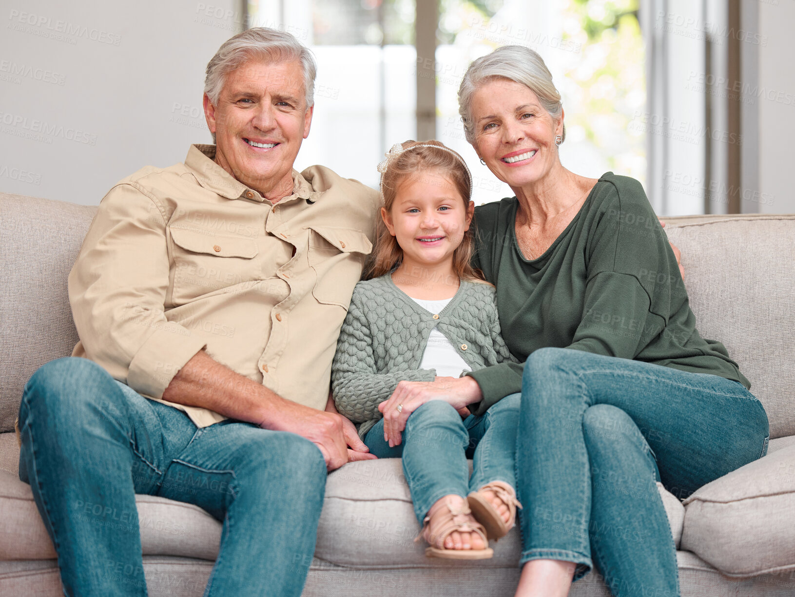 Buy stock photo Portrait of a mature couple bonding with their granddaughter on a sofa