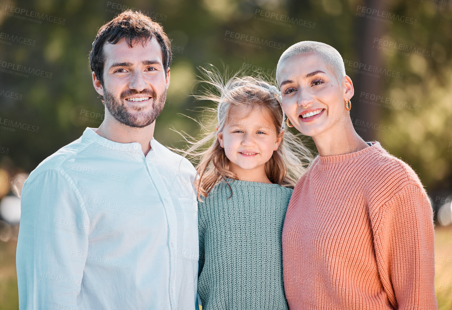 Buy stock photo Shot of a young couple and their daughter spending time outdoors