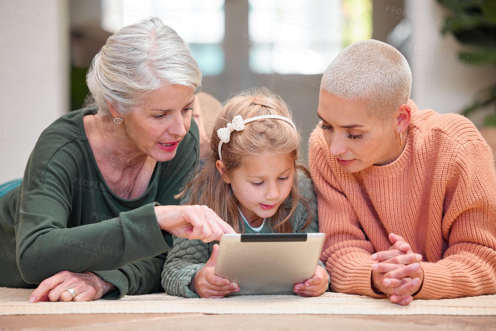 Buy stock photo Pointing, streaming and tablet with family in living room of home together for download or education. Girl, grandma and mother on floor in apartment for child development, growth or learning