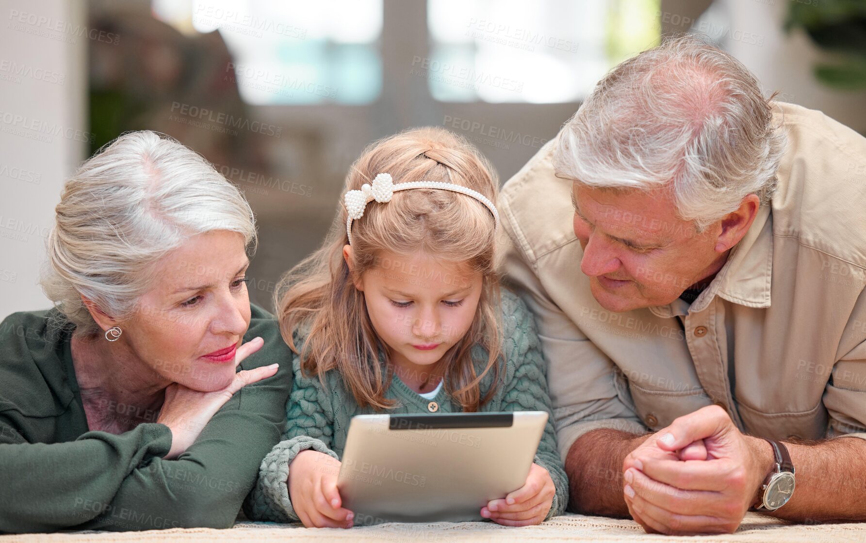 Buy stock photo App, download and tablet with family in living room of home together for education or streaming. Girl, grandparents and reading on floor in apartment for child development, growth or learning