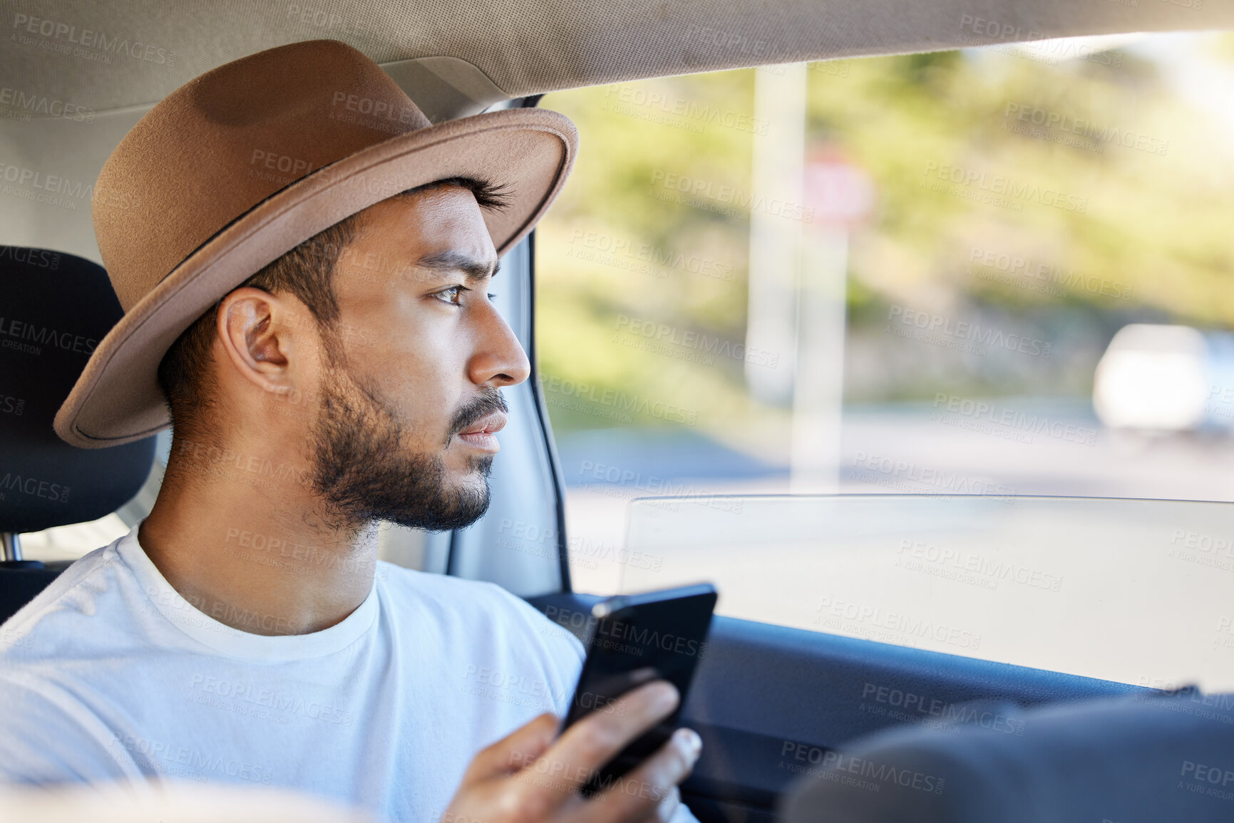 Buy stock photo Shot of a young man sitting in a car while using his phone