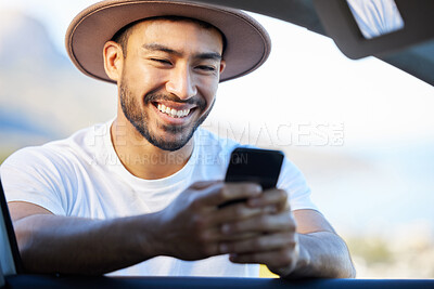 Buy stock photo Shot of a young man using a phone while standing outside of his car