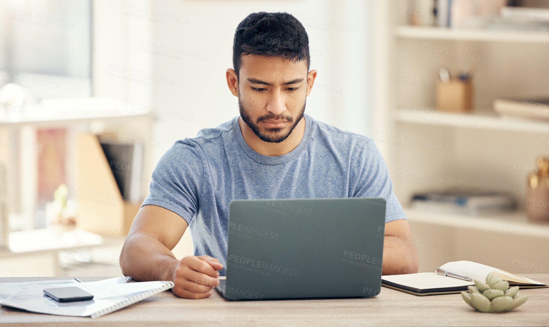 Buy stock photo Shot of a young businessman using a laptop in an office at work