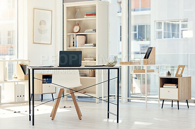 Buy stock photo Furniture, laptop and desk with chair in office for decor with shelves, art frame and technology. Files, interior and computer on table for creative career in empty, stylish and modern workplace.