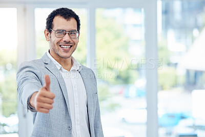 Buy stock photo Shot of a young businessman showing the thumbs up in a modern office