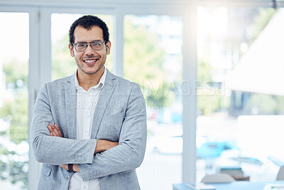 Buy stock photo Shot of a young businessman folding his arms in a modern office