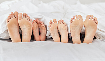 Buy stock photo Shot of a family laying barefoot on a bed at home
