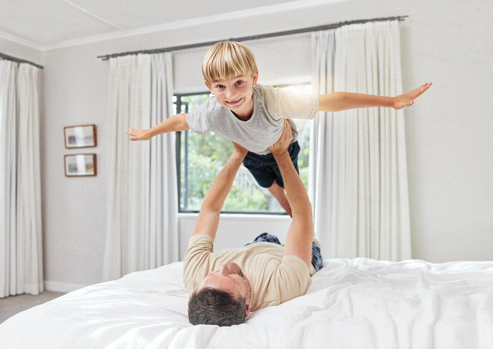 Buy stock photo Father, flying and playing with child on bed for bonding, weekend or playful holiday at home. Happy dad, kid or son with arms out for airplane, support or fun childhood together in bedroom at house