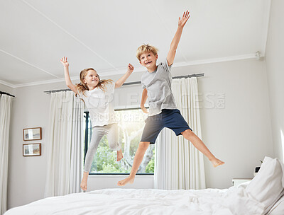Buy stock photo Shot of a brother and sister having fun while jumping on a bed together at home