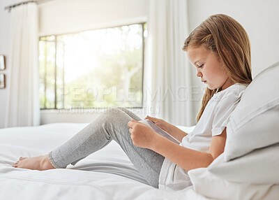 Buy stock photo Shot of a little girl using a digital tablet in bed at home