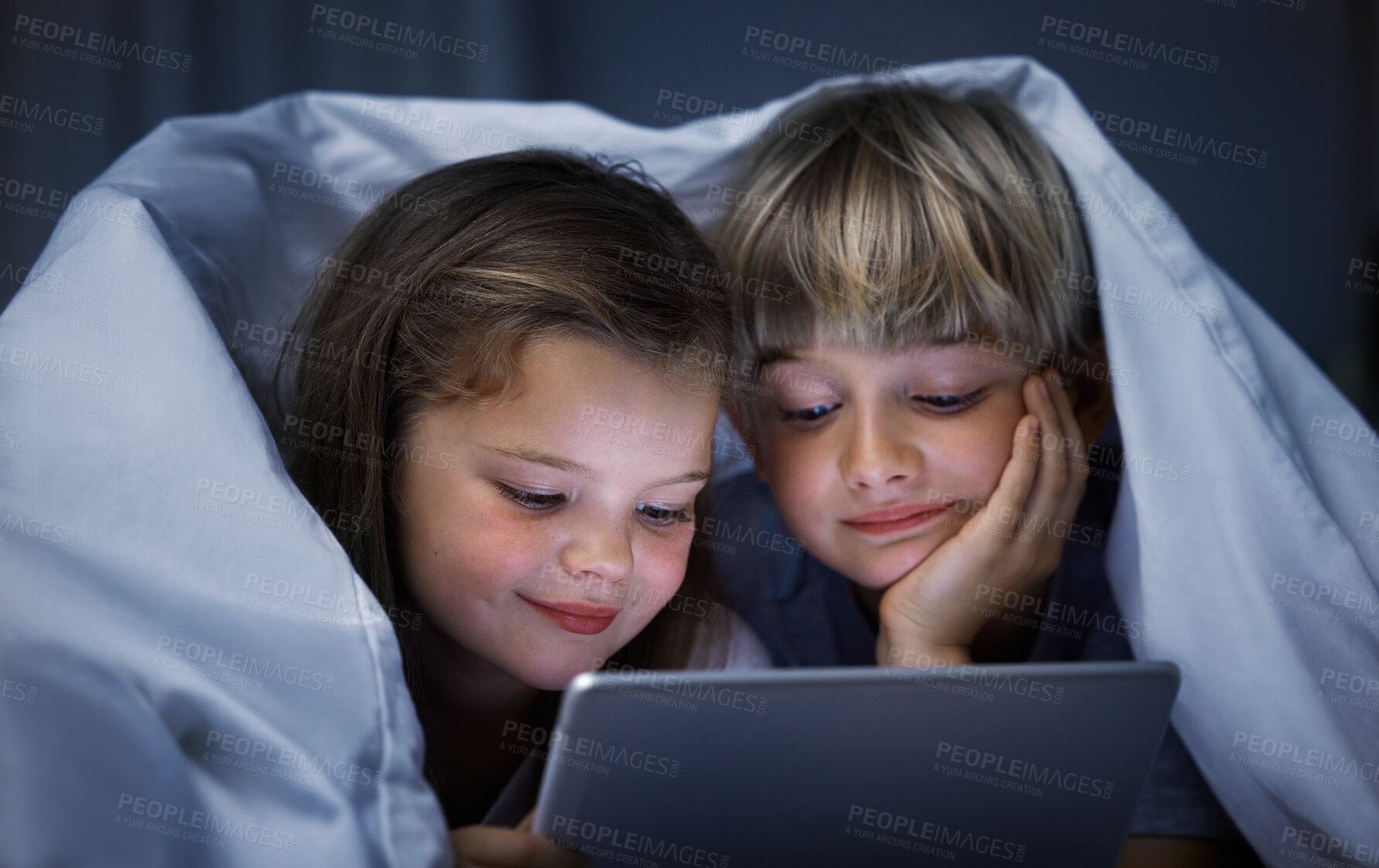 Buy stock photo Shot of a brother and sister using a tablet in bed at night