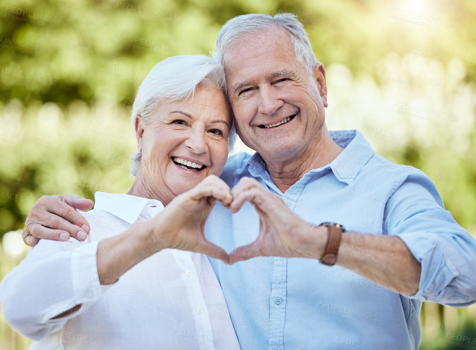 Buy stock photo Shot of a senior couple forming a heart shape with their hands while standing outside