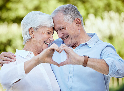 Buy stock photo Shot of a senior couple forming a heart shape with their hands while standing outside