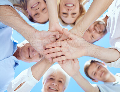 Buy stock photo Shot of a multi-generational family stacking their hands on top of each other while standing outside