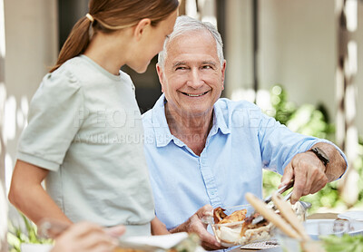 Buy stock photo Shot of a little girl standing next to her grandfather at the dining table