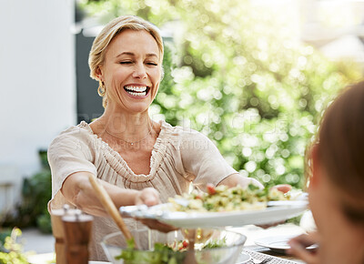 Buy stock photo Shot of a woman passing food around at the dining table