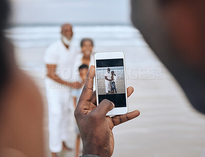 Buy stock photo Cropped shot of an unrecognizable man taking a picture of a mature couple and their grandson at the beach