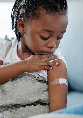 Buy stock photo Shot of an adorable little girl with a plaster on her arm after an injection