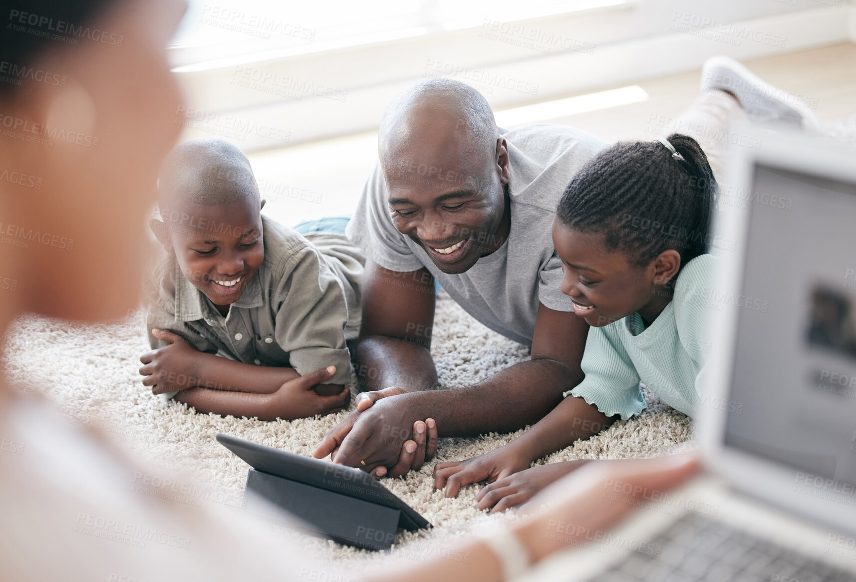 Buy stock photo Shot of a family using s tablet while laying on the floor at home