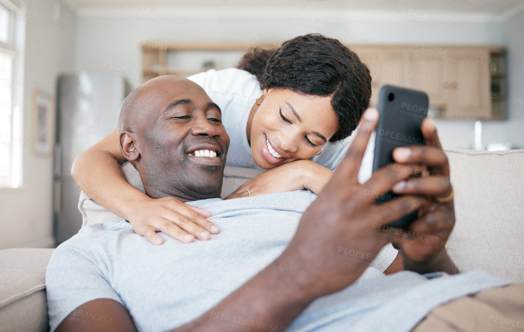 Buy stock photo Black couple, home and smile with smartphone on couch with hug for social media post and funny videos. People, relationship and happy or laughing on sofa in living room on internet for memes