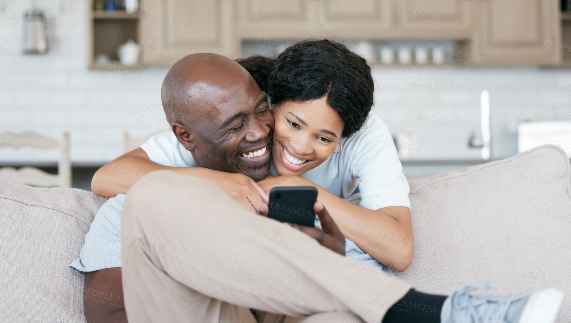 Buy stock photo Black couple, home and happy with smartphone on couch with hug for social media post and funny videos. People, relationship and smile or laughing on sofa in living room on internet for memes