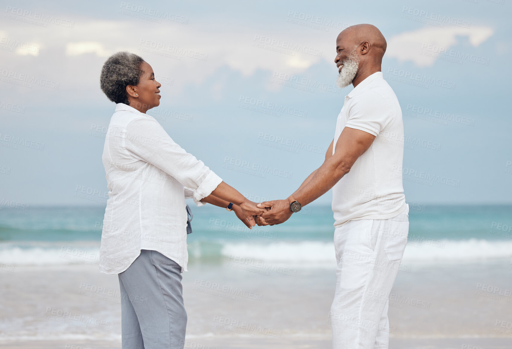 Buy stock photo Happy, holding hands and senior black couple on beach for travel, vacation or getaway with bonding. Love, connection and elderly man and woman by ocean for retirement holiday together in Morocco.